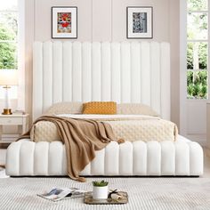 a white bed sitting in a bedroom on top of a hard wood floor next to a window