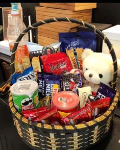 a teddy bear sitting in a basket filled with snacks