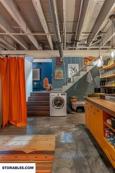 an industrial style kitchen with orange curtains and wood cabinets, including a washer and dryer