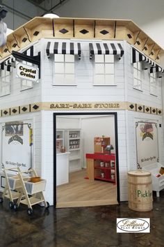 a white building with black and white awnings on the roof is decorated like a store