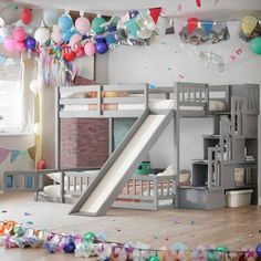 there is a bunk bed with a slide in the middle and balloons all around it