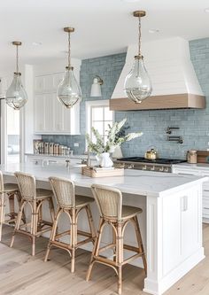 a large kitchen with white cabinets and wooden stools next to an island in the middle