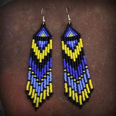 two pairs of beaded earrings with yellow and blue beads on top of a brown surface