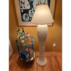 a lamp sitting on top of a wooden floor next to a table