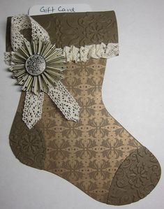 a christmas stocking made out of brown paper with white lace and a flower on it