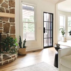 a living room filled with furniture and a fire place in front of a stone wall