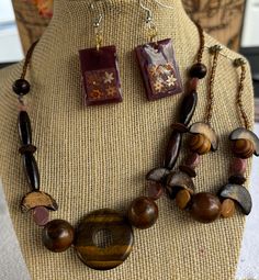 This unique and necklace and bracelet features a beautiful blend of natural wood beads, accented by a stunning tiger's eye centerpiece. The set has earthy tones and organic shapes create a relaxed and free-spirited vibe. Perfect for adding a touch of boho chic to your wardrobe, this necklace is a versatile and eye-catching piece Bohemian Wood Beaded Jewelry, Nature-inspired Brown Necklaces With Natural Variations, Nature-inspired Brown Necklace With Natural Variations, Adjustable Wood Jewelry Nature-inspired, Adjustable Wood Jewelry In Nature-inspired Style, Handmade Artisan Mahogany Jewelry, Nature-inspired Brown Round Bead Jewelry, Adjustable Nature-inspired Wooden Jewelry, Artisan Handmade Mahogany Jewelry