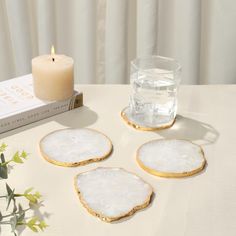 three white marble coasters sitting on top of a table next to a candle