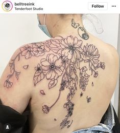 the back of a woman's shoulder with flowers and butterflies on her left side