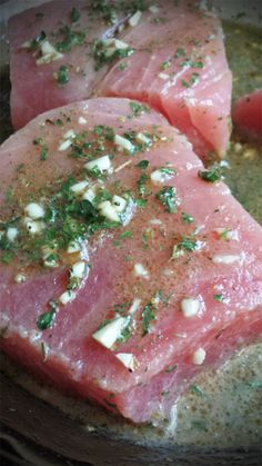 two pieces of meat with herbs on them in a frying pan