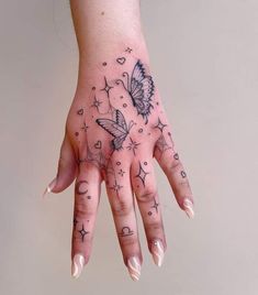 a woman's hand with tattoos on it and butterflies in the sky above her