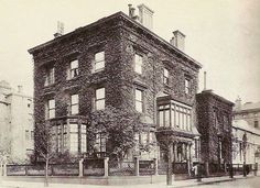 an old black and white photo of a building with ivy growing on it's side