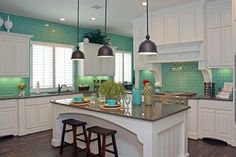 a kitchen with white cabinets and green tile backsplash, counter tops and stools