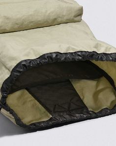 an open sleeping bag sitting on top of a white floor next to a black pillow