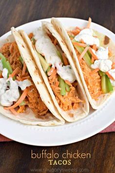 three chicken tacos on a white plate with carrots, celery and sour cream