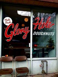 two empty chairs sitting in front of a doughnut shop's window with the word glory written on it