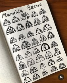 an open notebook with many different designs on the cover and writing in black ink next to a pen