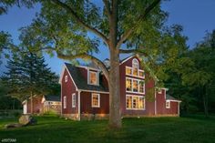 a large red house sitting on top of a lush green field next to a tree