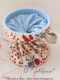 a blue and red flowered cloth covered container with a bow tie around the top