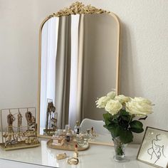 a white dresser topped with a mirror and vase filled with flowers