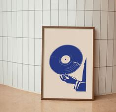 a blue vinyl record being held up by a person's hand in front of a tiled wall