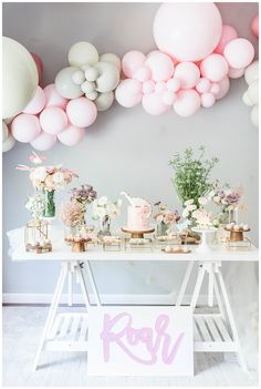 a table topped with lots of pink and white balloons