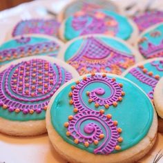 decorated cookies are arranged on a plate with pink and blue icing in the middle