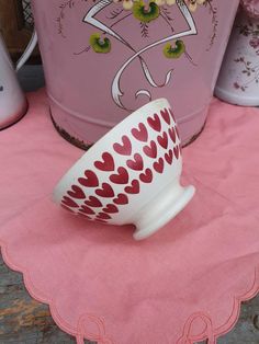 a white and red bowl sitting on top of a pink table cloth next to a metal pail