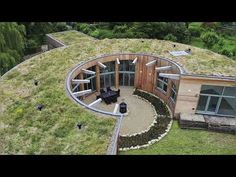 an aerial view of a circular house with green roof and grass on the top floor