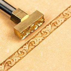 a close up of a gold colored object on a table with a black pen in it