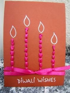 an orange card with three candles on it and pink ribbon tied around the edges that says diwali wishes