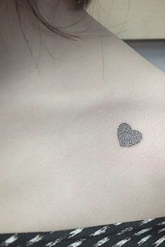 a woman's chest with a fingerprint heart tattoo on the left side of her shoulder