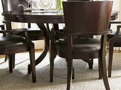 a dining room table with chairs and a vase on top of it in front of a window