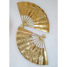 two gold fans sitting on top of a white table