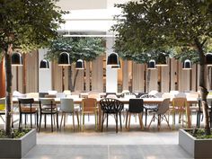 an indoor dining area with tables and chairs in front of wooden paneled partitions