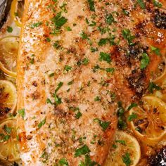 a piece of fish covered in herbs and lemons sitting on top of a pan