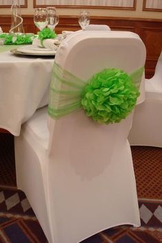 a white chair with green ruffles on it and place settings at the back