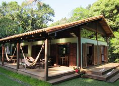 a small wooden house with hammocks on the porch and covered decking area