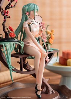 a figurine is sitting on a chair holding a magnifying glass in her hand