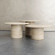 three tables sitting on top of each other in front of a white wall and cement floor