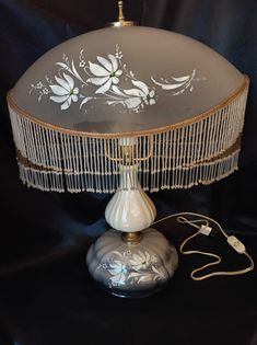 a lamp that is sitting on top of a black tablecloth with white flowers painted on it