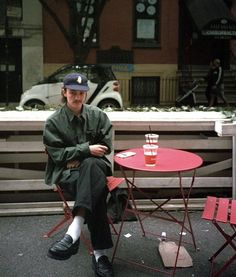 a man sitting at a table with a drink in front of him on the street