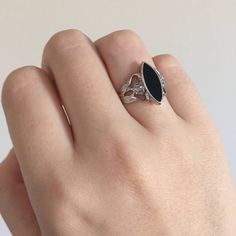 a person's hand wearing a ring with an oval shaped black stone on it