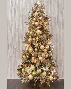 a decorated christmas tree with gold and silver ornaments on the top, in front of a wood paneled wall