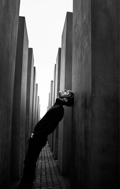 a man leaning against the wall with his head in the air and looking up at something