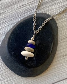 Cairns have long been used to mark trails and paths so that we don’t lose our way in the wilderness. Take a little bit of the trail with you wherever you go with this dainty cairn necklace. Three hand drilled pebbles and a heishi glass bead are hung on small stainless steel chain. Comfortable and easy to wear. Stainless steel chain and findings won’t tarnish, and won’t irritate sensitive skin. -Stainless steel findings and chain -Hand drilled natural beach pebbles and an indigo glass heishi bead Pebble Jewelry Without Drilling Holes, Cairn Necklace, Beach Pebbles, Heishi Necklace, Three Hands, Blue Flats, Heishi Beads, The Wilderness, Cairns