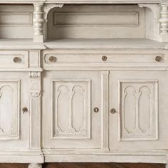 an old white painted buffet with drawers and cupboards on it's sideboard