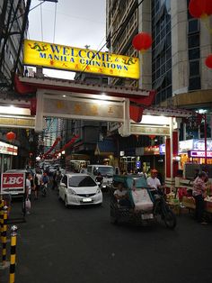 a busy street with cars and people walking on the sidewalk under a neon sign that reads san francisco market chinatown