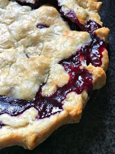 a pie with blueberry topping sitting on top of a black countertop next to a knife