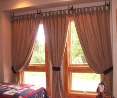 a bedroom with two large windows and a bed in front of the window has a quilt on it